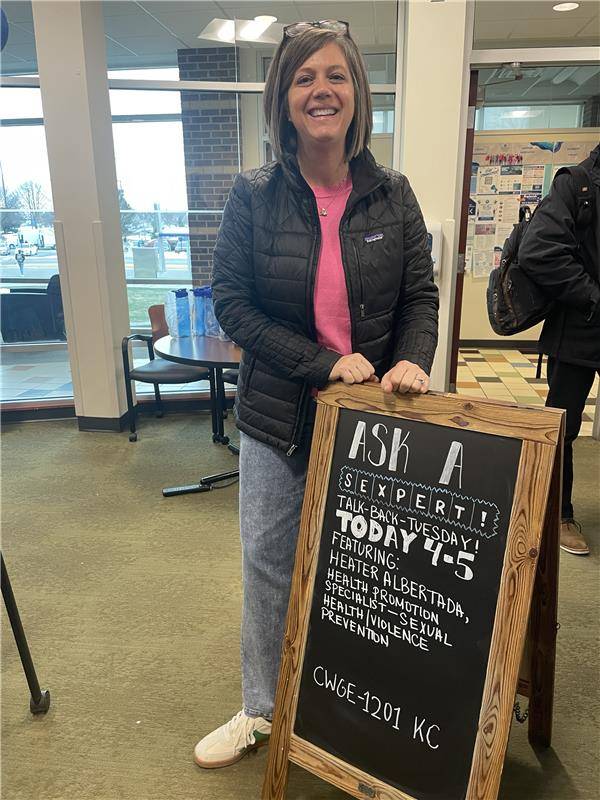 Image of a smiling woman in front of a sign with her name on it